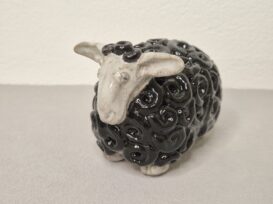 Schaf in schwarz mit weißem Kopf, handgemacht, dient als Dekoration für Ostern. Die Schafwolle werden durch kleine eingedrehte Schnecken dargestellt.